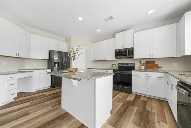 a kitchen with granite countertop white cabinets and stainless steel appliances