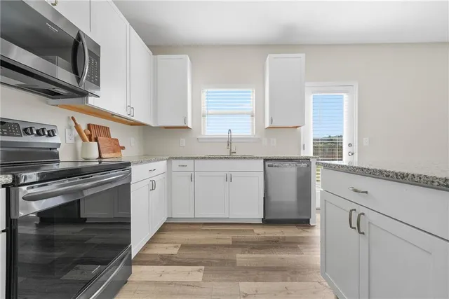 a kitchen with granite countertop a sink stainless steel appliances and cabinets