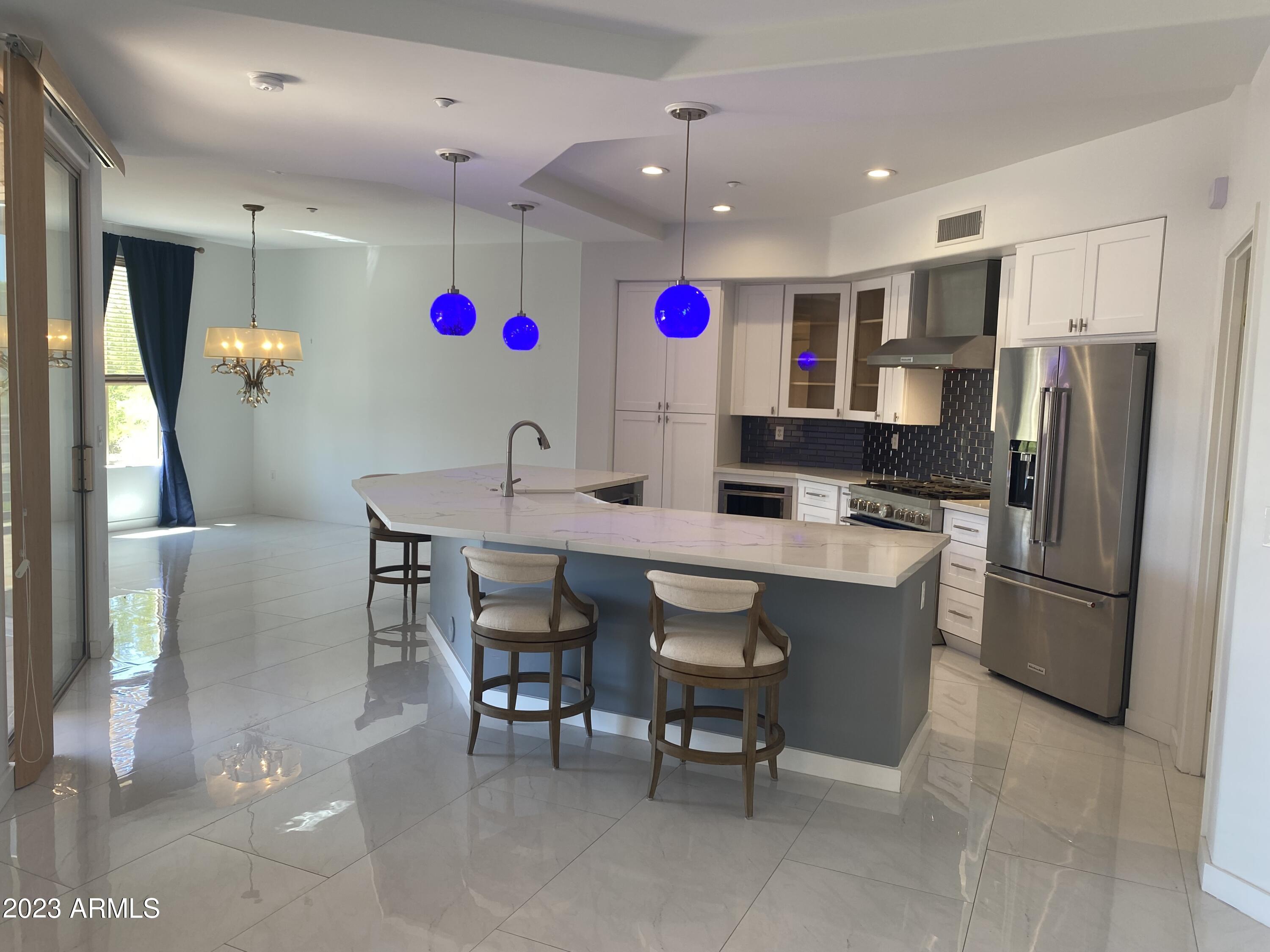 a kitchen with stainless steel appliances kitchen island granite countertop a table chairs and a refrigerator