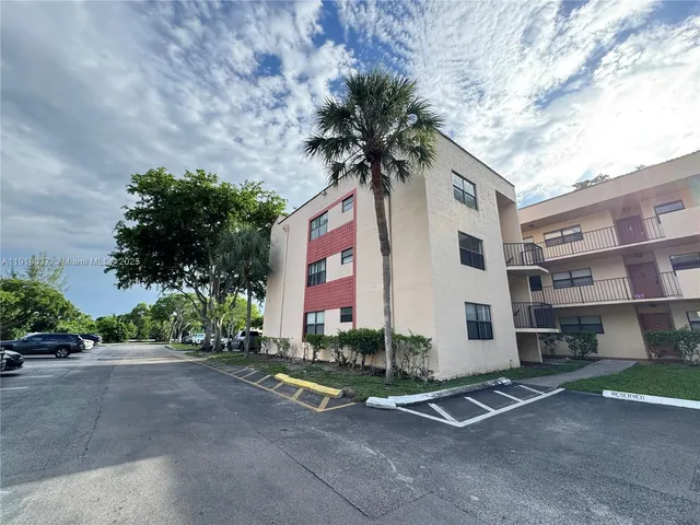 a front view of a building with garage and plants