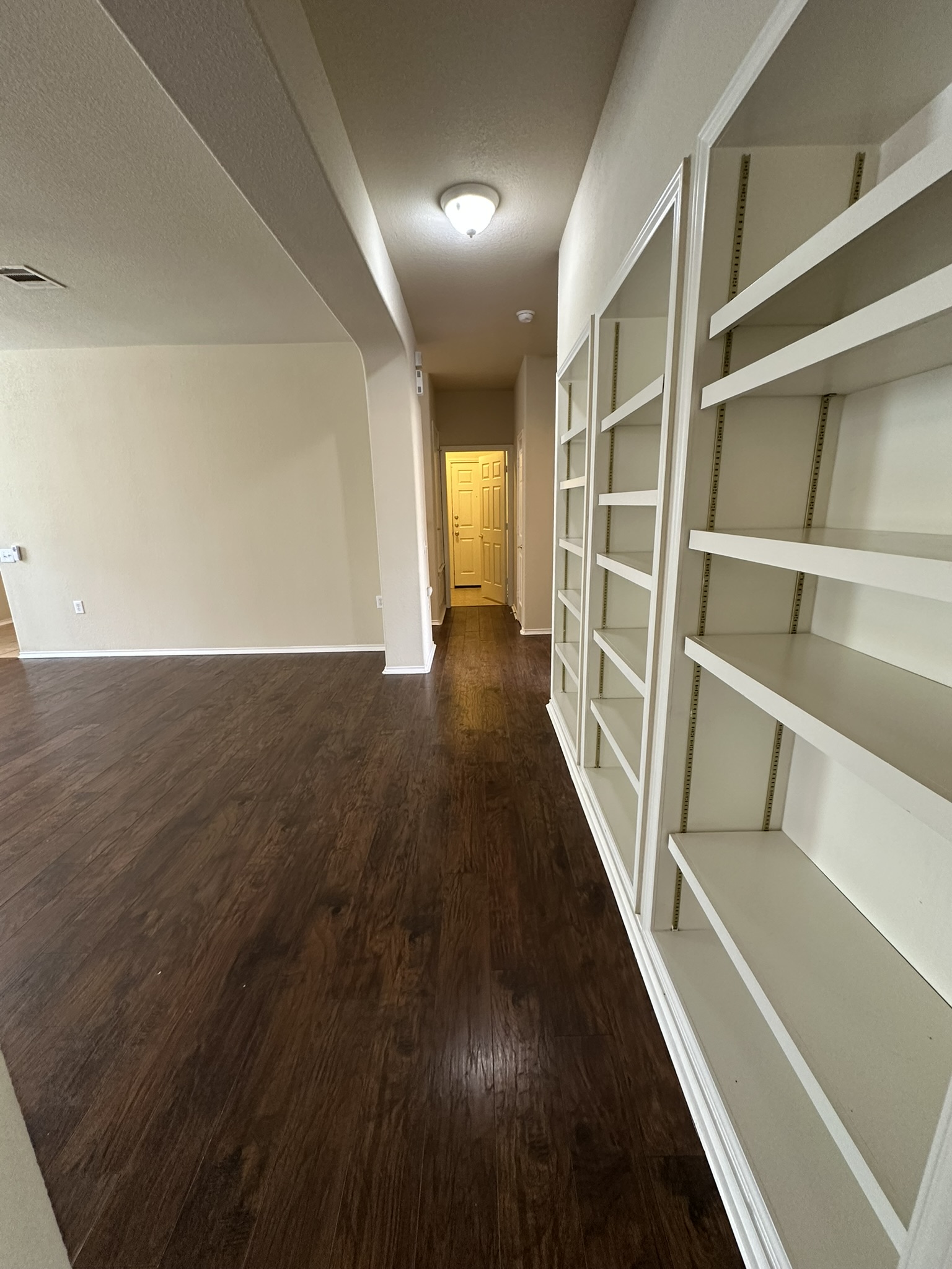 4507 Peach Grove Road Austin, TX 78744 - Photo 22 of 35 Rich wood-look flooring and custom built-in shelving define this welcoming transitional hallway.