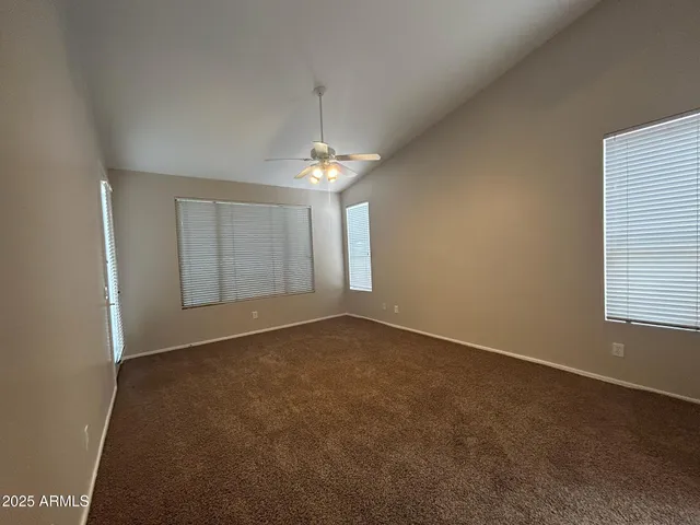 an empty room with chandelier fan and windows