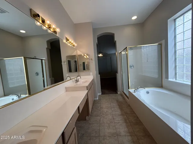 a bathroom with a tub a double vanity sink and mirror