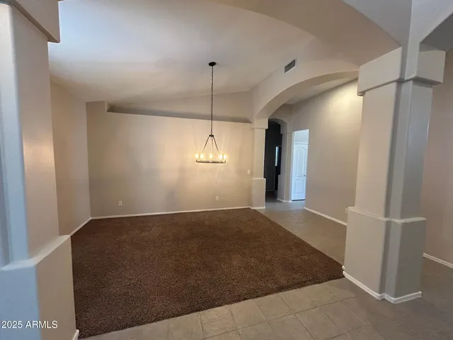 a view of an empty room with window and chandelier fan