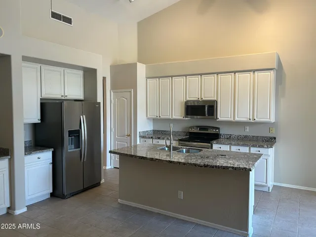 a kitchen with refrigerator a microwave a sink and cabinets