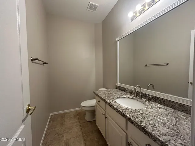a bathroom with a granite countertop sink a toilet and a mirror