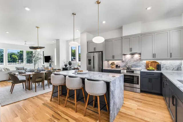 a kitchen with stainless steel appliances kitchen island granite countertop a table chairs and a stove