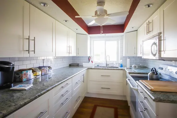 a kitchen with granite countertop stainless steel appliances sink stove and cabinets
