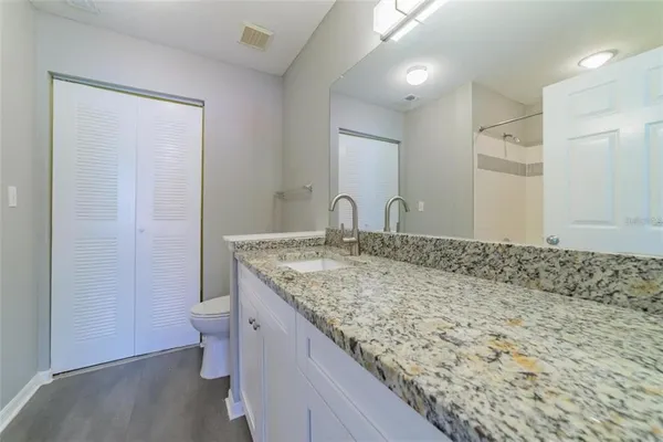 a bathroom with a granite countertop sink a toilet and a shower
