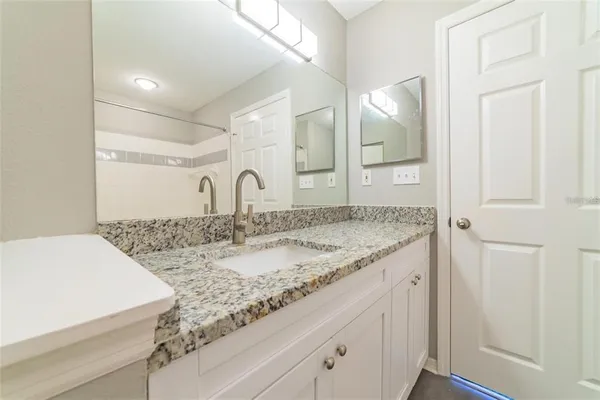 a bathroom with a granite countertop sink and a mirror
