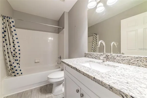 a bathroom with a granite countertop sink a toilet and shower