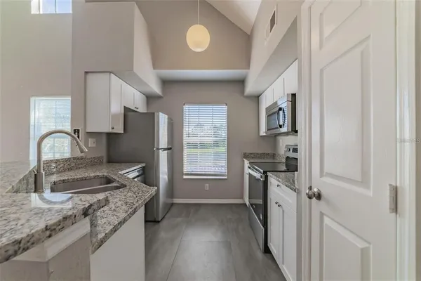 a kitchen with granite countertop a sink stove and refrigerator