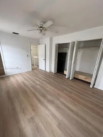 an empty room with wooden floor fireplace and windows