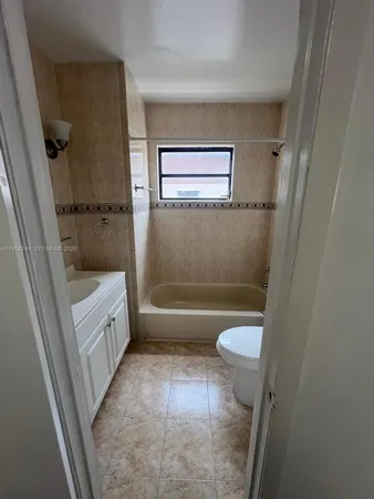 a bathroom with a granite countertop toilet and a tub