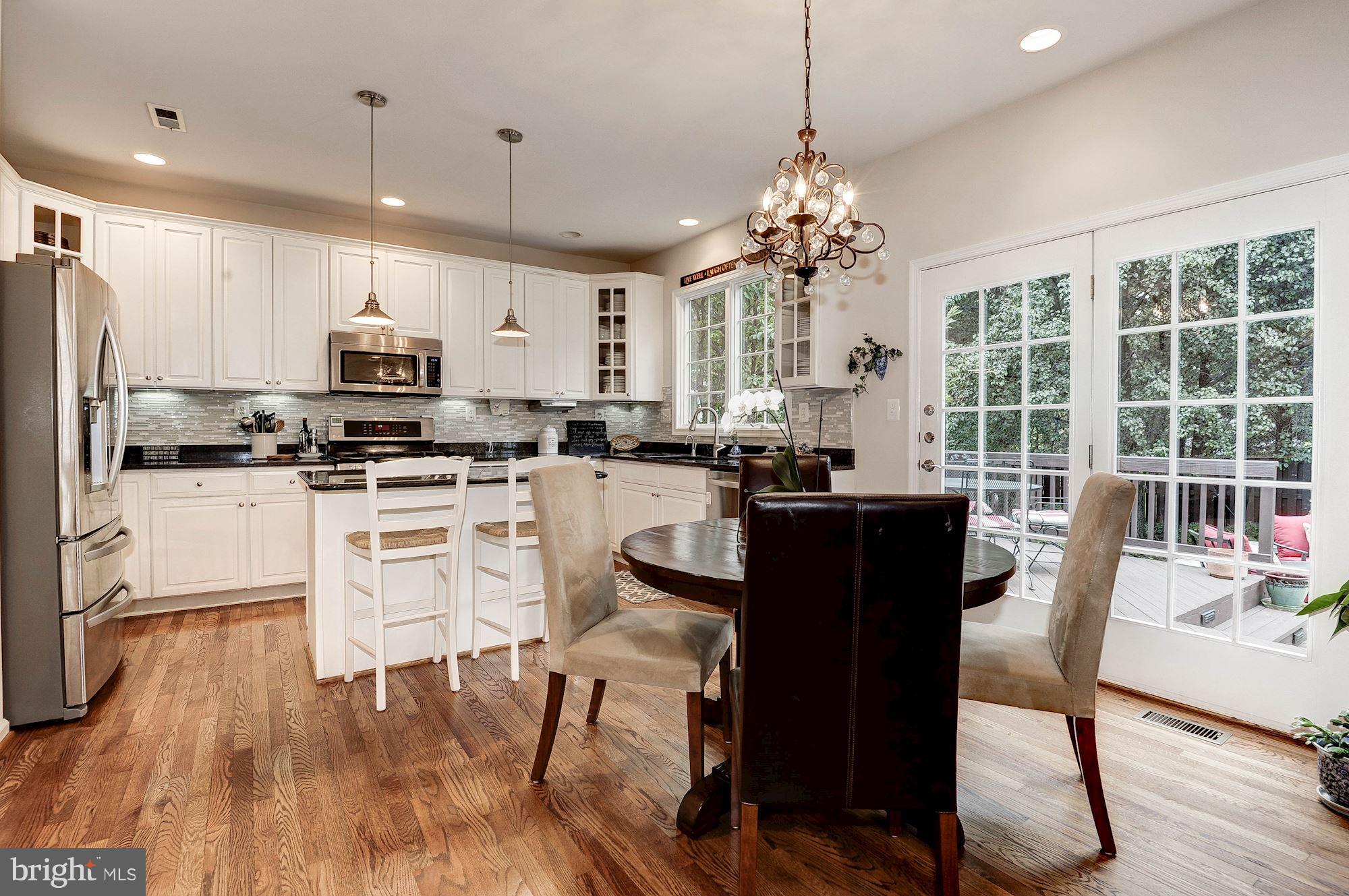 1328 Murray Downs Way Reston, VA 20194 - Photo 8 of 30 a kitchen with stainless steel appliances granite countertop a stove a refrigerator a sink dishwasher a dining table and chairs with wooden floor