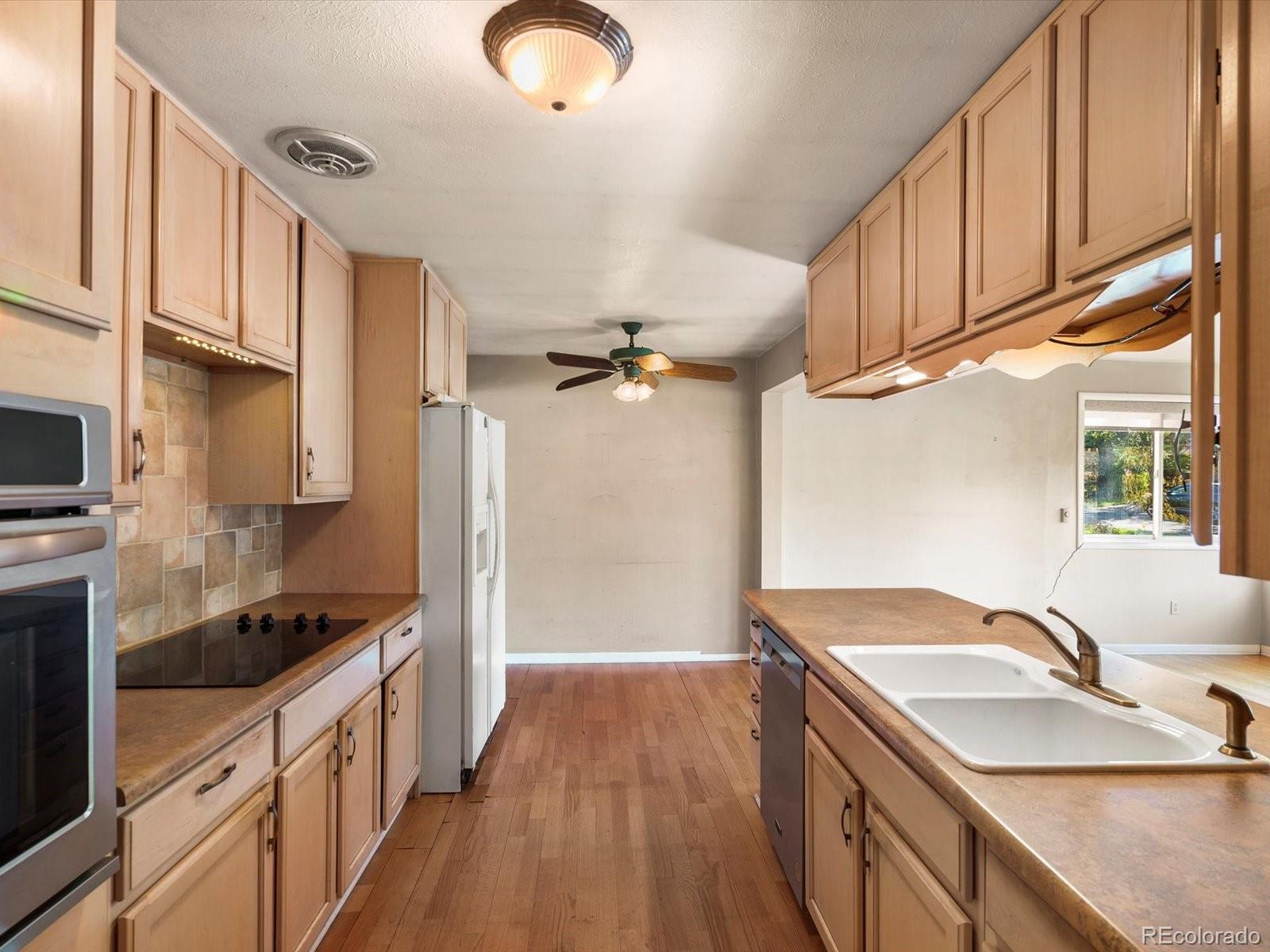 9815 West 37th Avenue Wheat Ridge, CO 80033 - Photo 6 of 50 a kitchen with granite countertop a sink stainless steel appliances wooden floor and cabinets