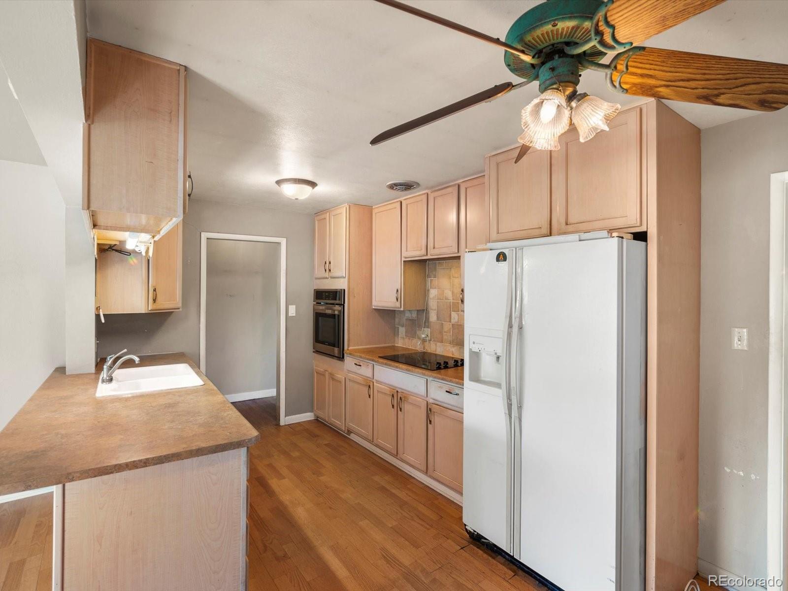9815 West 37th Avenue Wheat Ridge, CO 80033 - Photo 7 of 50 a kitchen with a refrigerator a sink and cabinets