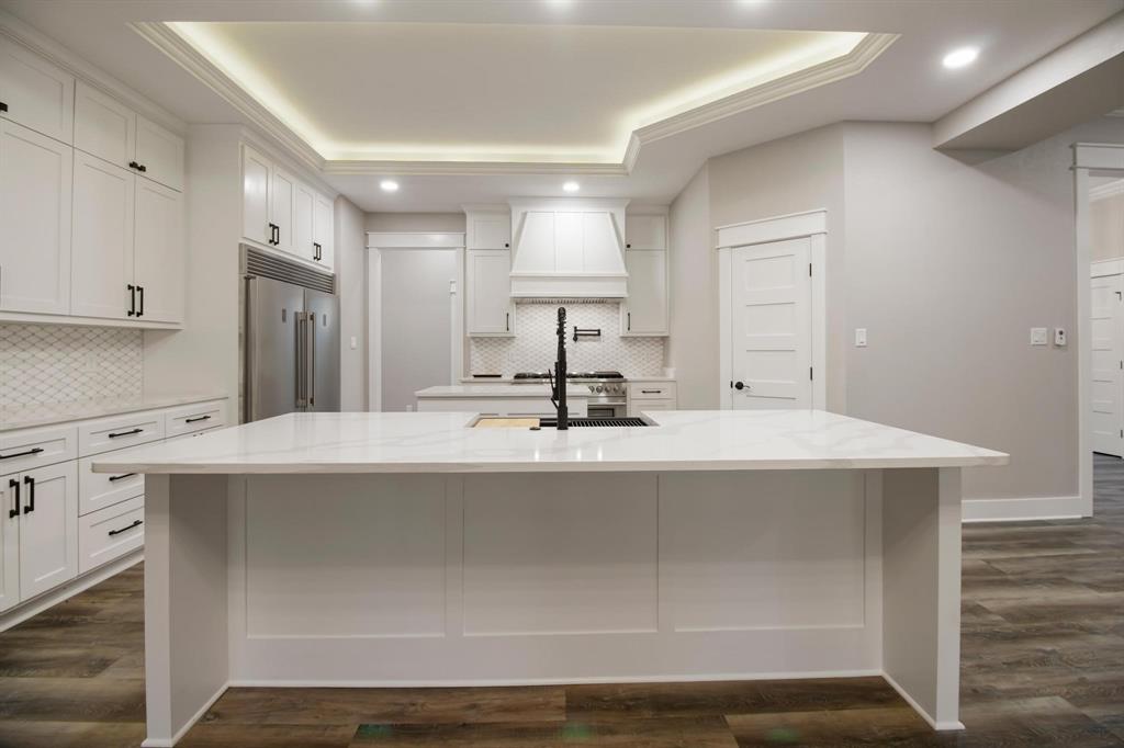 800 Stone Chimney Road Bullard, TX 75757 - Photo 13 of 40 a kitchen with kitchen island a sink a stove and white cabinets