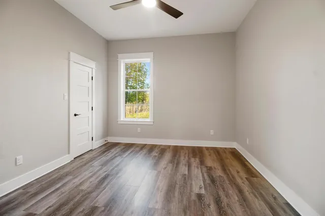 en empty room with windows and ceiling fan
