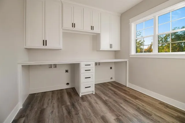 a room with white cabinets and wooden floor