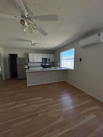 a view of a livingroom with a kitchen stove wooden floor and window