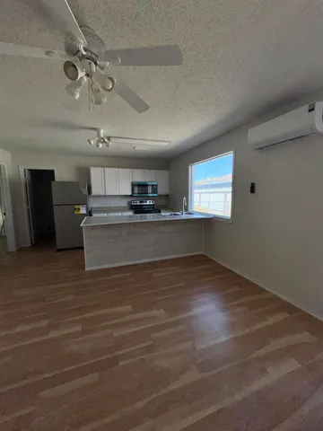 a view of a livingroom with a kitchen stove wooden floor and window