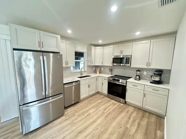a kitchen with white cabinets stainless steel appliances and a refrigerator