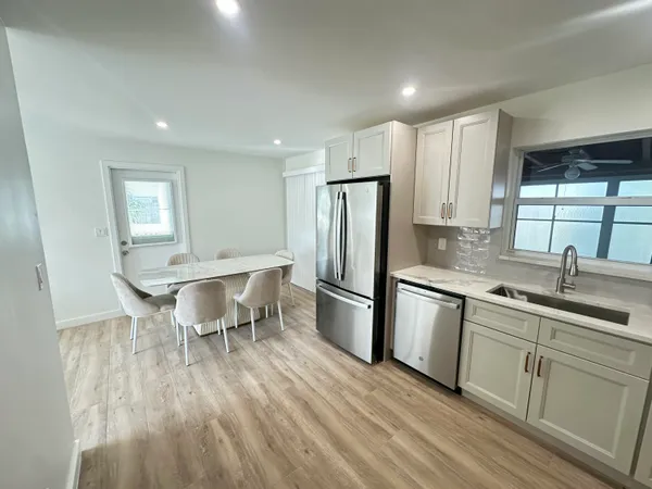 a kitchen with stainless steel appliances granite countertop a sink a stove a refrigerator and island with wooden floor