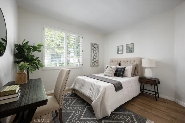 a bedroom with a bed table chair and a window