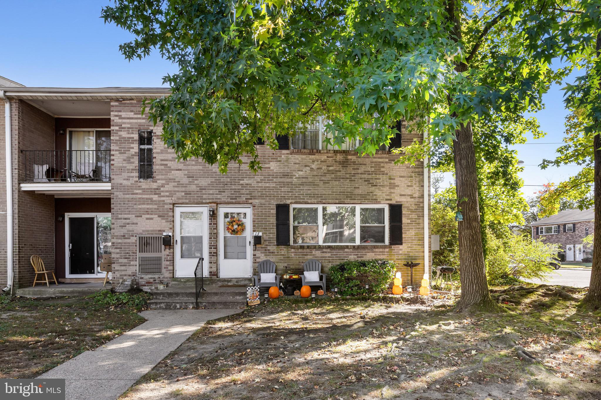 1294 Cooper Street, Unit E13 Edgewater Park, NJ 08010 - Photo 1 of 15 a view of a brick house with large windows and a large tree
