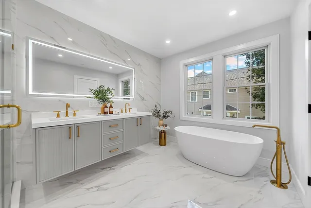 a spacious bathroom with a double vanity sink a mirror a bathtub and next to a window