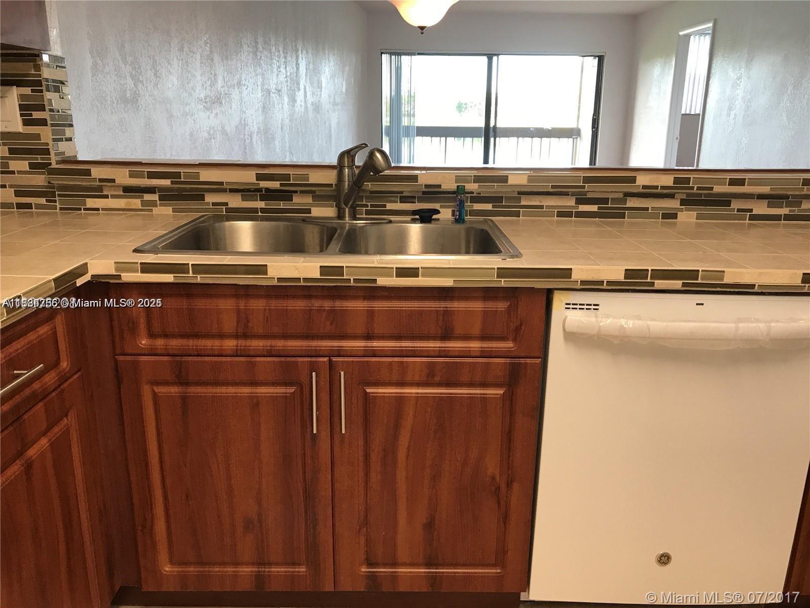 10288 Northwest 9th St Circle, Unit 205 Miami, FL 33172 - Photo 4 of 11 a kitchen with a sink a stove cabinets and a window