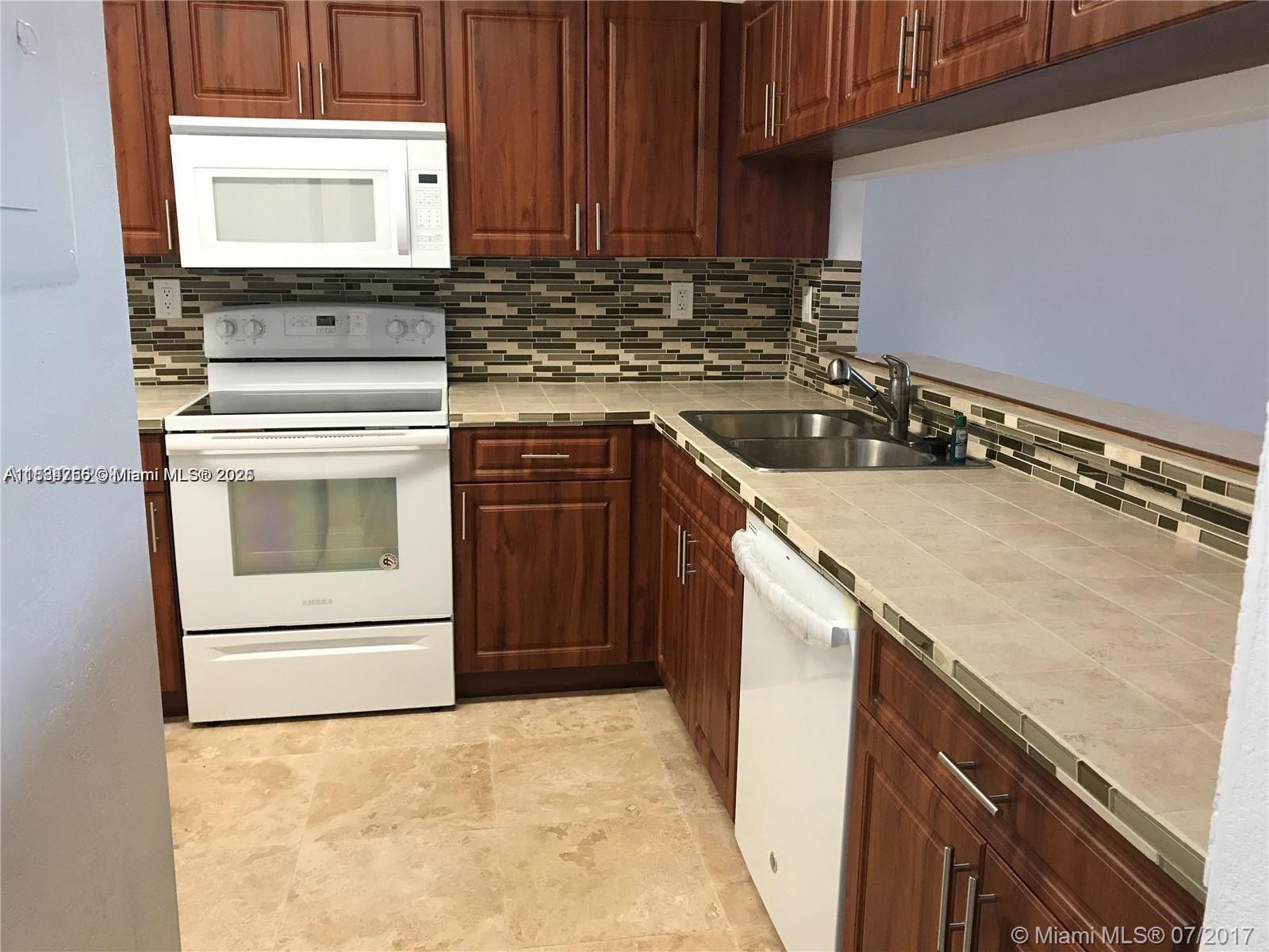 10288 Northwest 9th St Circle, Unit 205 Miami, FL 33172 - Photo 5 of 11 a kitchen with a sink stove and cabinets