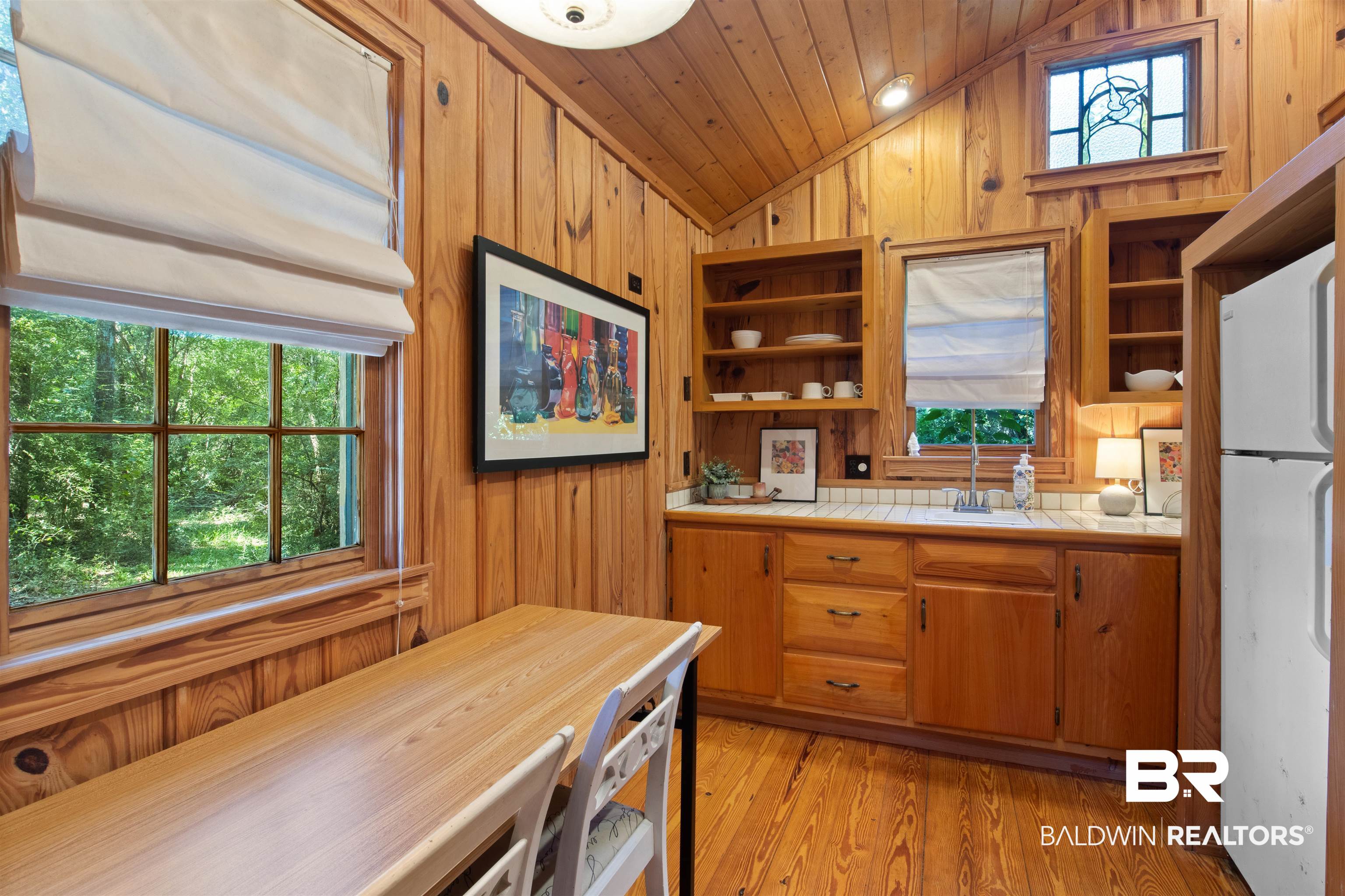 15100 Vasko Road Silverhill, AL 36576 - Photo 29 of 51 Kitchen with vaulted ceiling, wood walls, light hardwood flooring. Small stained glass windows throughout cabin are highlighted by the west facing light at kitchen sink.
