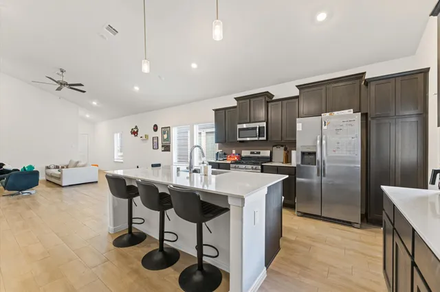 a kitchen with stainless steel appliances a table chairs refrigerator and cabinets