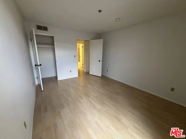 a view of an empty room with wooden floor and closet