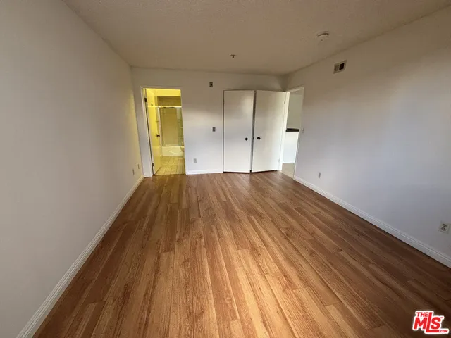 a view of a big room with wooden floor and windows