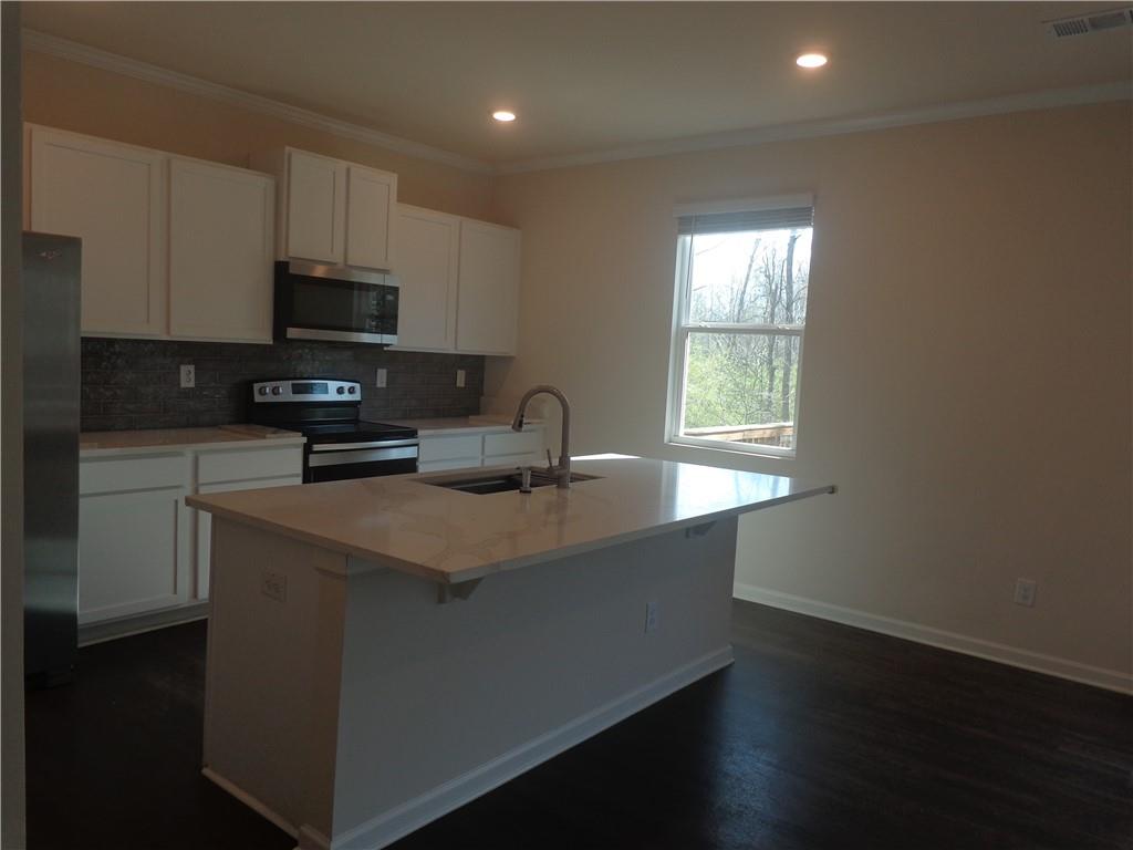 132 Russell Road Pendergrass, GA 30567 - Photo 18 of 50 a kitchen with stainless steel appliances a sink a stove a microwave and wooden cabinets