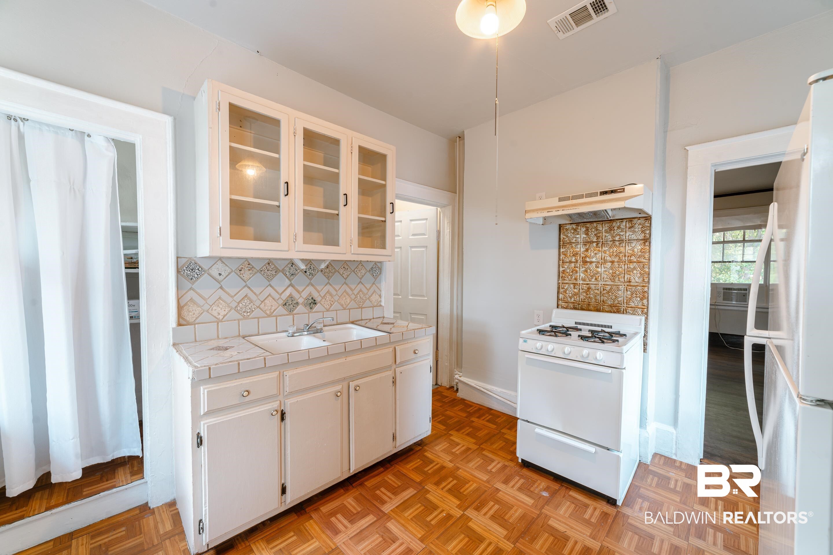 312 1st Street Mobile, AL 36611 - Photo 9 of 29 Kitchen with tile counters, sink, white cabinetry, white appliances, and tasteful backsplash