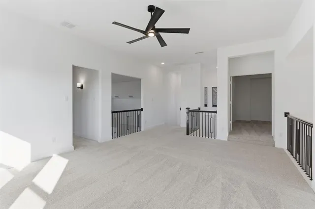 a view of empty room with wooden floor and ceiling fan