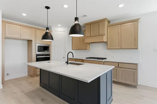 a kitchen with stainless steel appliances a sink a stove a refrigerator and cabinets