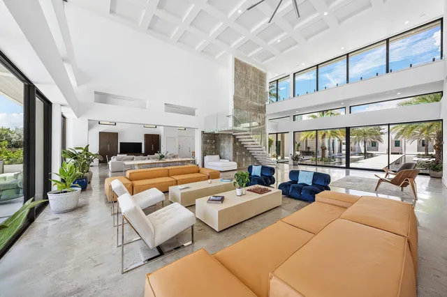 a living room with furniture and three large window