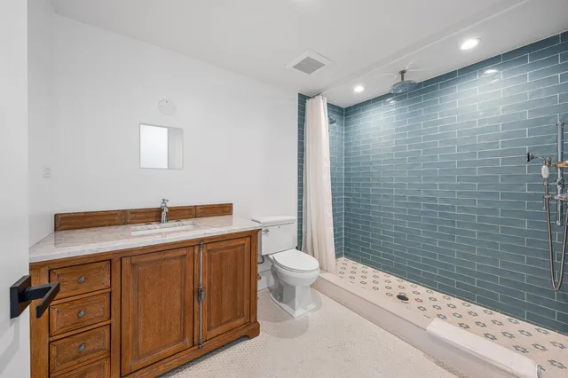 a bathroom with a granite countertop sink a toilet and shower