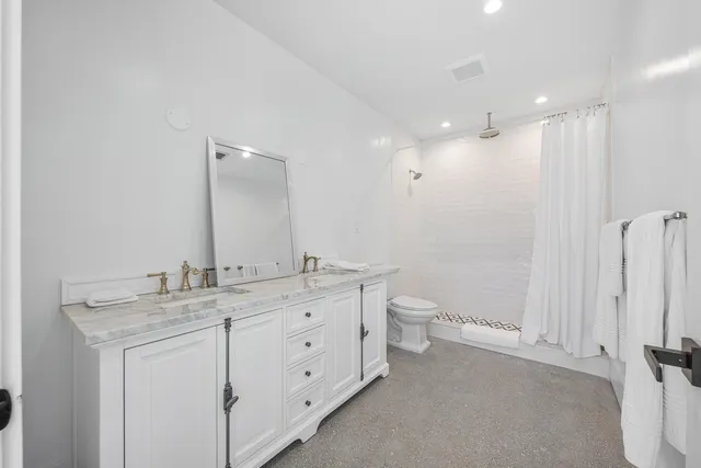 a bathroom with a granite countertop sink a toilet and a mirror