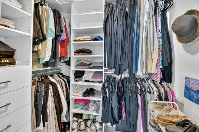 a view of walk in closet with clothes and shoes