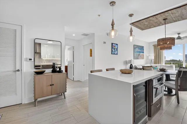 a living room with stainless steel appliances kitchen island a sink dishwasher a stove and a dining table with wooden floor