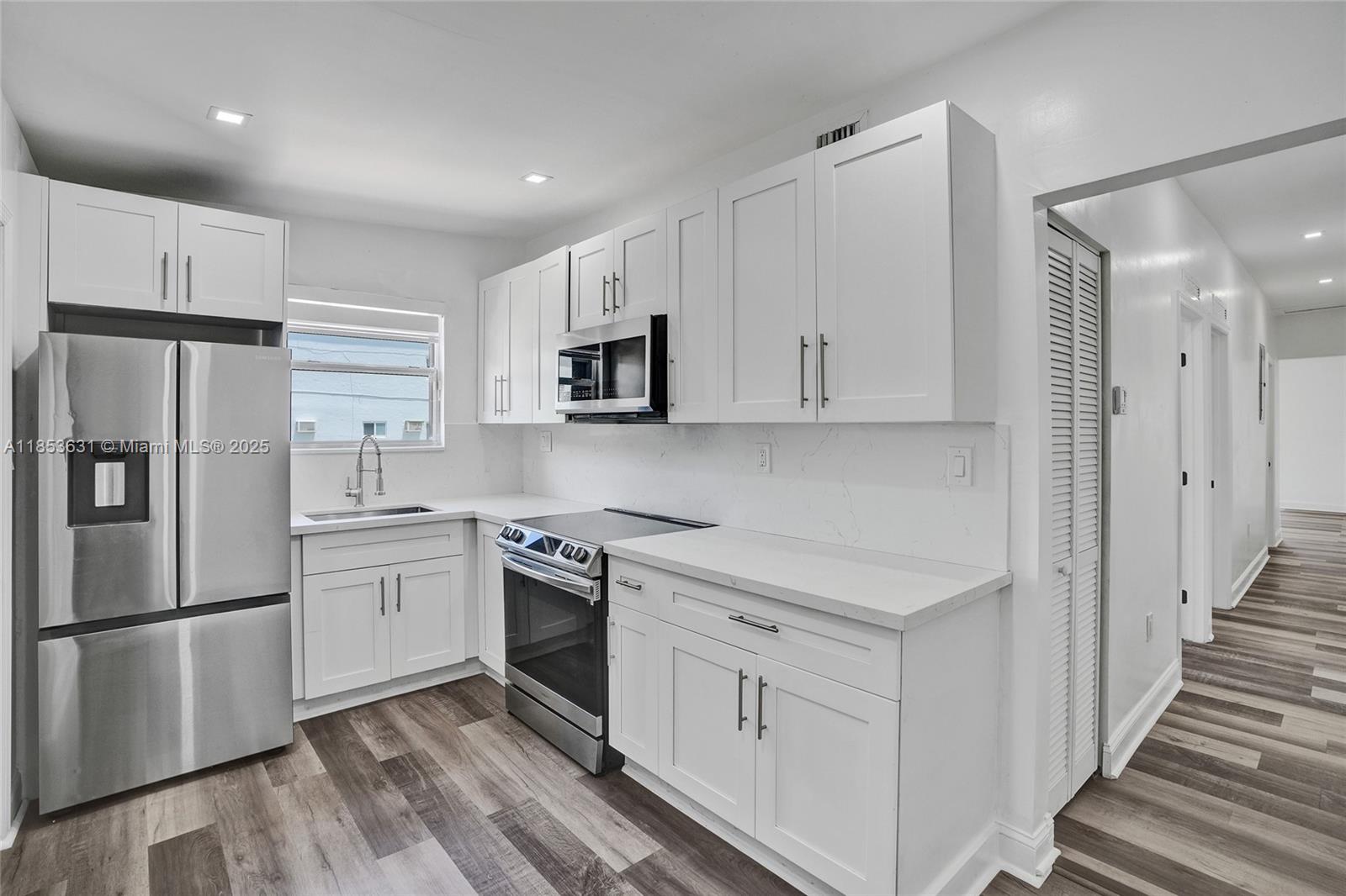 2135 Southwest 4th Street Miami, FL 33135 - Photo 5 of 28 a kitchen with white cabinets stainless steel appliances and a refrigerator