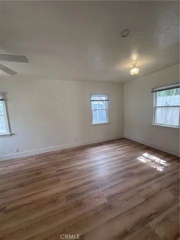 a view of an empty room with window and wooden floor