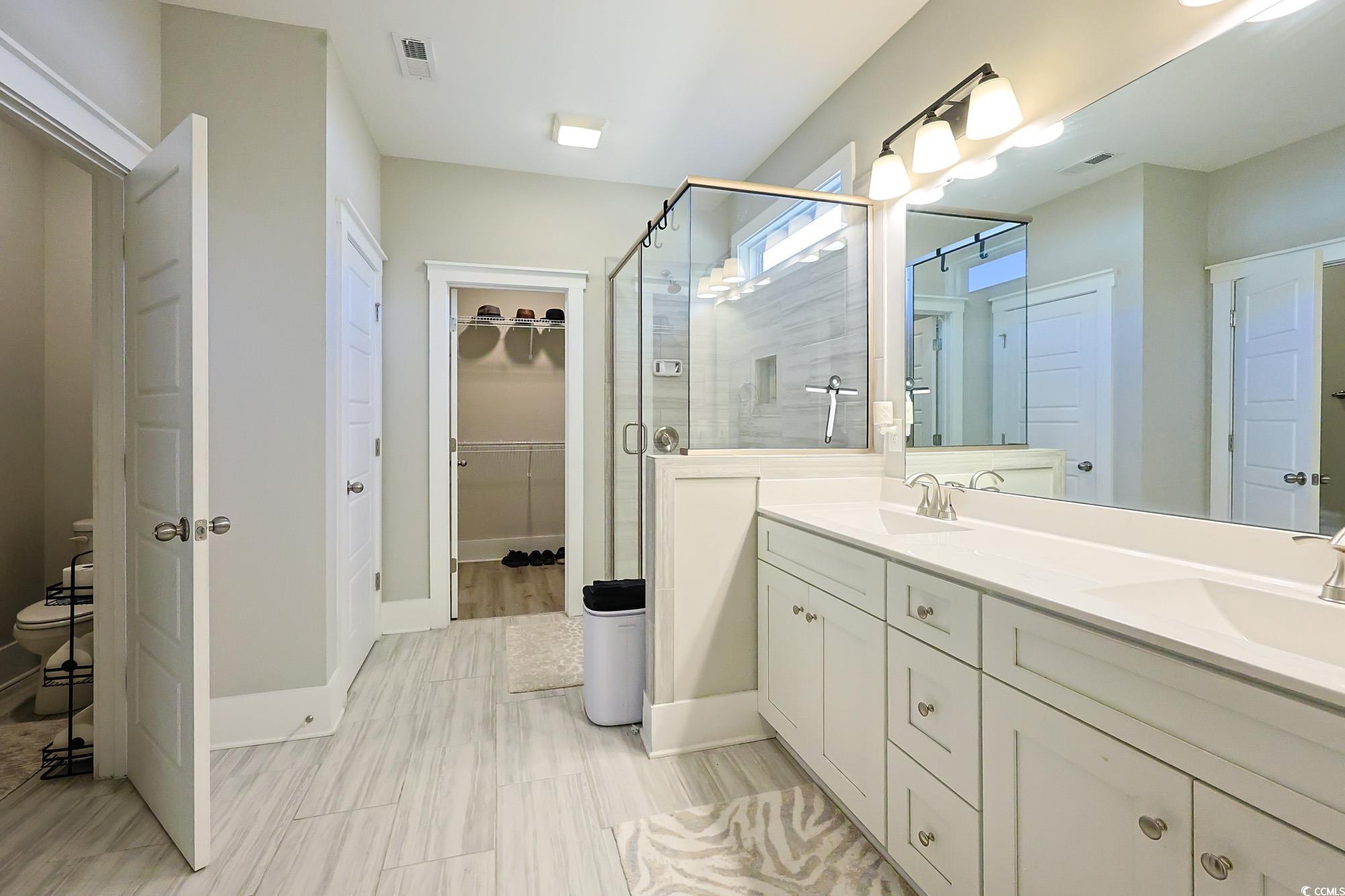 669 Pacific Commons Drive Surfside Beach, SC 29575 - Photo 13 of 36 Bathroom with double vanity, a walk in closet, and a stall shower