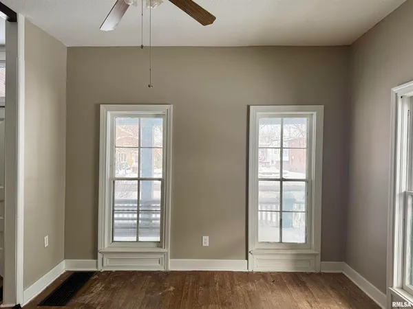 an empty room with wooden floor and windows